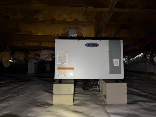 AprilAire dehumidifier installed on blocks over a white crawl space liner