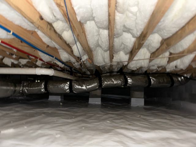 Spray foam insulation on the underside of a floor above an encapsulated crawl space